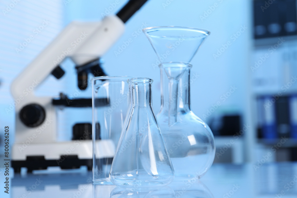 Laboratory analysis. Different glassware and microscope on white table indoors Laboratory analysis. Different glassware and microscope on white table indoors