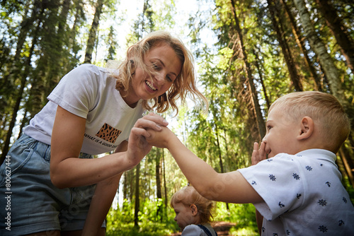 Mother and Son Enjoying a Sunny Day in the Forest and daughter on the background. Life style photo