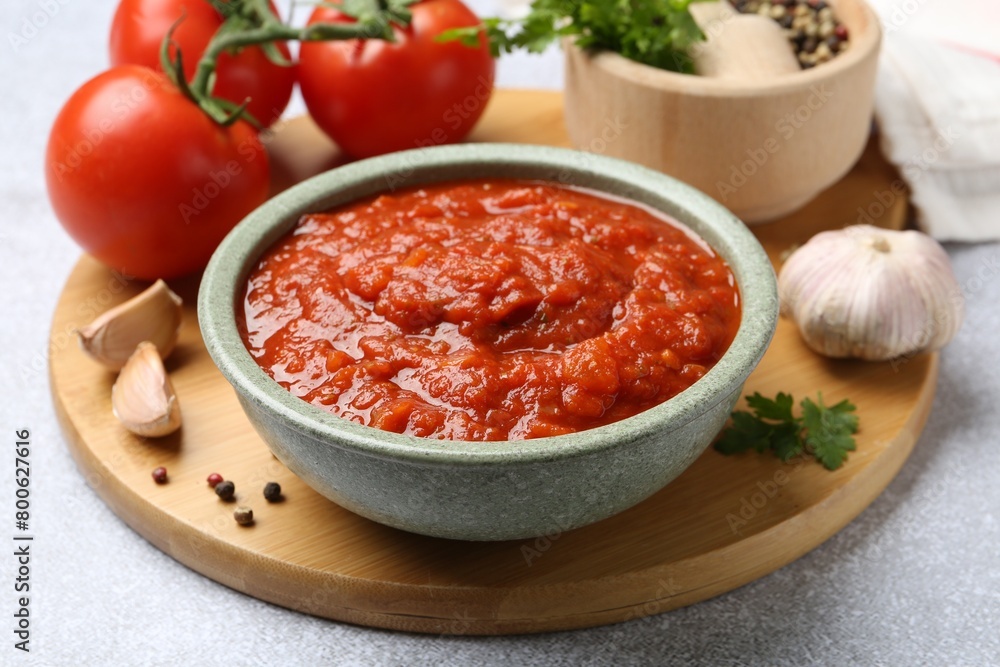 Homemade tomato sauce in bowl and fresh ingredients on light grey table, closeup Homemade tomato sauce in bowl and fresh ingredients on light grey table, closeup