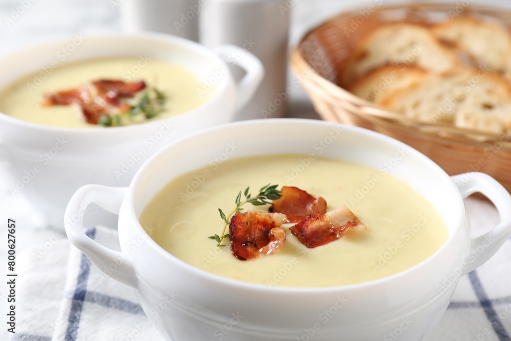 Tasty potato soup with bacon and rosemary in bowls on white table, closeup Tasty potato soup with bacon and rosemary in bowls on white table, closeup