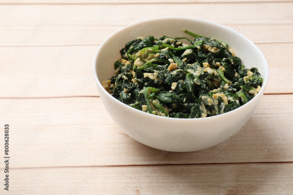 Tasty spinach dip with eggs in bowl on light wooden table, space for text Tasty spinach dip with eggs in bowl on light wooden table, space for text