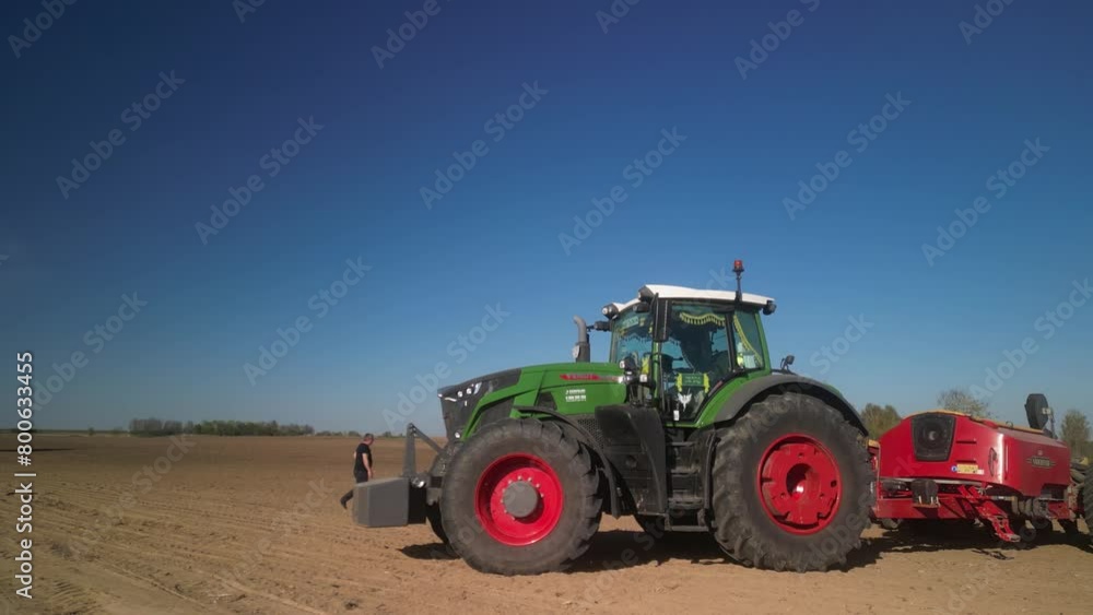 Green tractor works on the field planting sugar beet in spring in Ukraine Green tractor works on the field planting sugar beet in spring in Ukraine