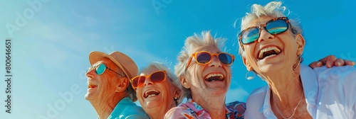 A group of happy senior people with sunglasses laughing and having fun at the beach on a sunny day