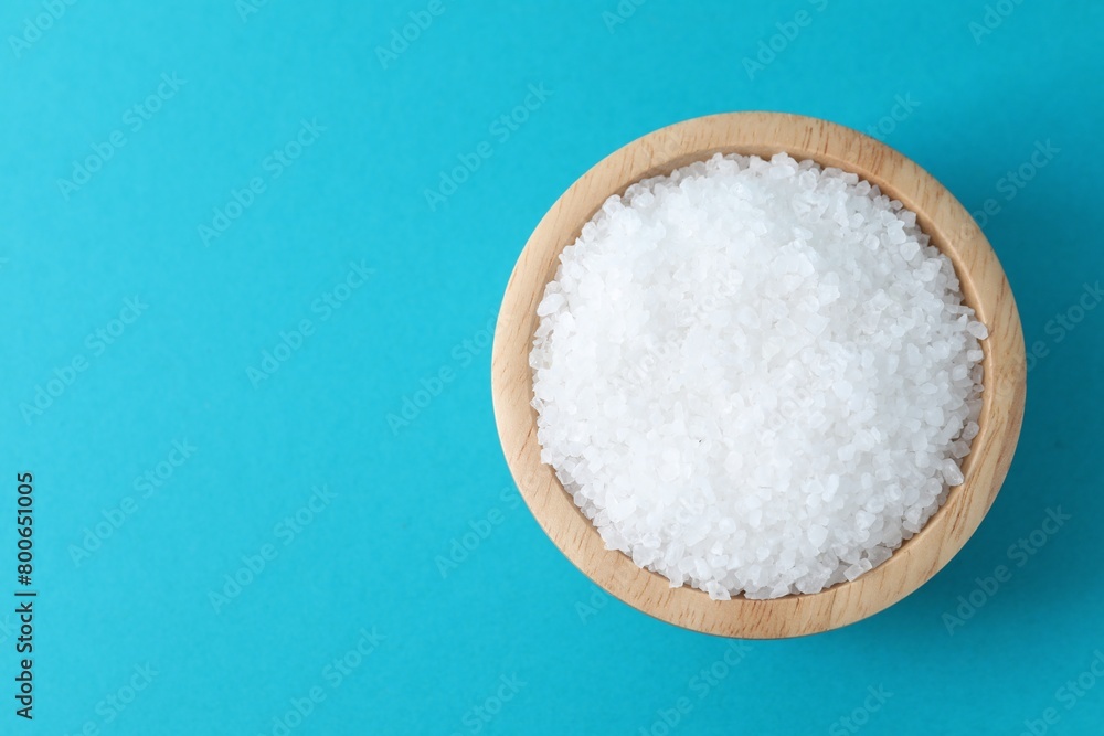 Organic white salt in bowl on light blue background, top view. Space for text Organic white salt in bowl on light blue background, top view. Space for text