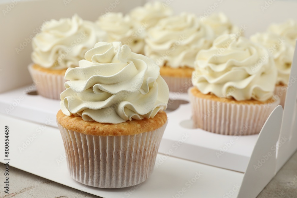 Tasty cupcakes with vanilla cream in box, closeup Tasty cupcakes with vanilla cream in box, closeup