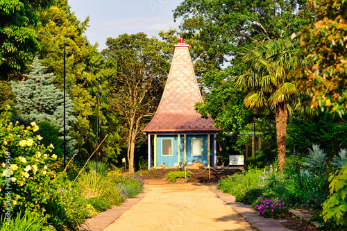A sunny view of a pointed-roof cottage or hut at the botanical garden JC Raulston Arboretum in Raleigh, North carolina USA.