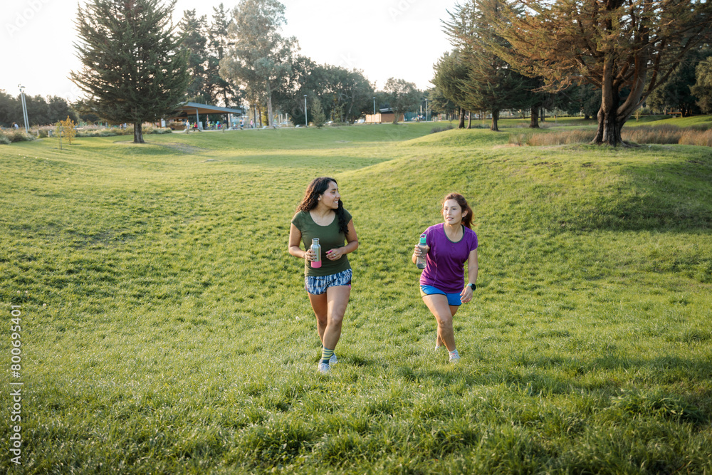 Fitness Friends: Two Latin Women Walking on the grass in the Park after running exercise at sunset. Fitness Friends: Two Latin Women Walking on the grass in the Park after running exercise at sunset.