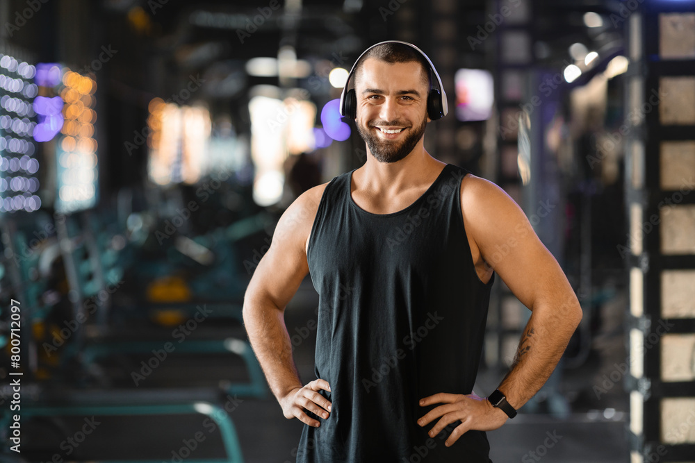 Fototapeta premium Handsome Millennial Man With Headphones Standing in Gym