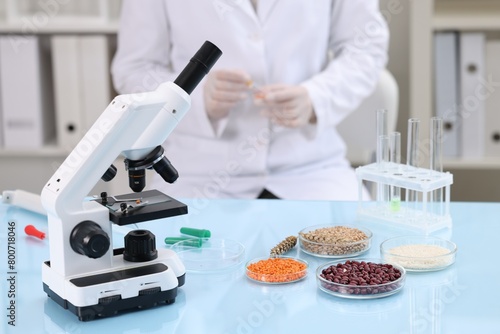 Quality control. Food inspector working in laboratory, focus on microscope and petri dishes with different products