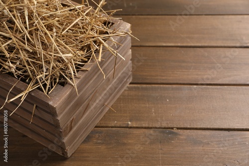 Dried straw in crate on wooden table, space for text