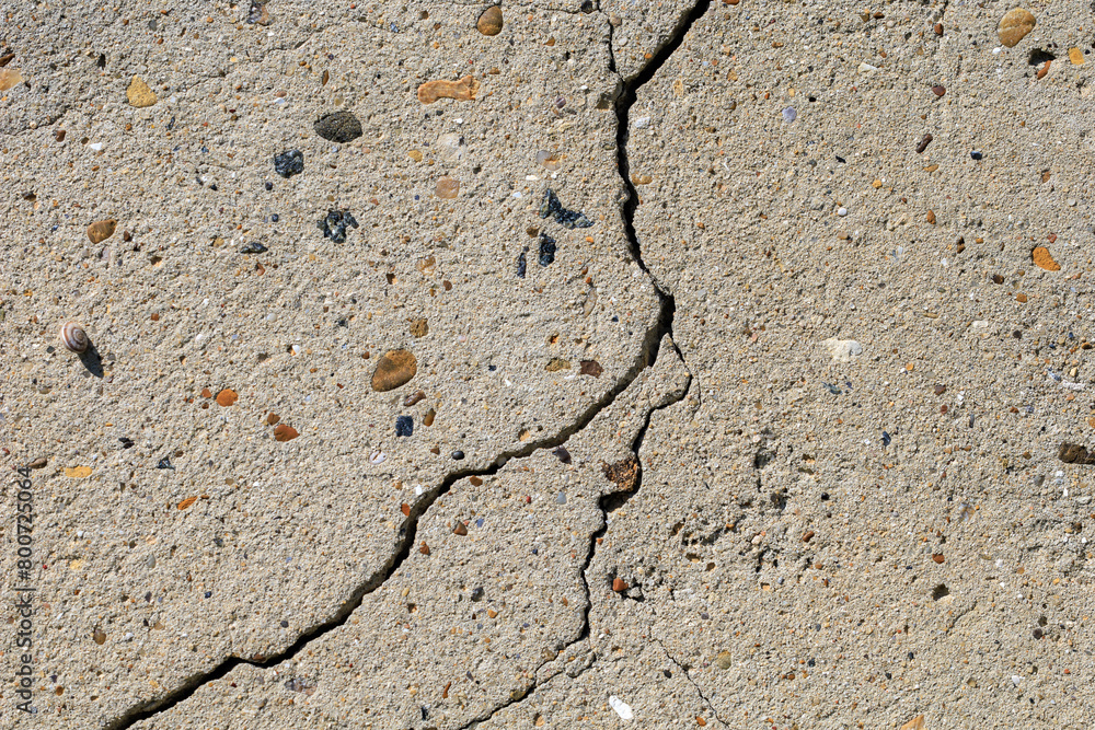 A cracked concrete surface with pebbles and rocks scattered across it A cracked concrete surface with pebbles and rocks scattered across it