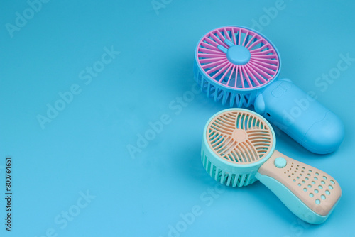 Kipas angin mini or portable mini fan with pastel color. Isolated blue background.