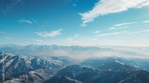 A mountain range is visible from the window of a plane flying at high altitude. The rugged peaks and valleys stand out against the clear sky, creating a stunning landscape.