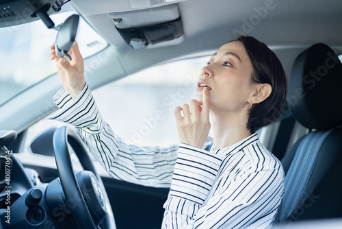 車内のミラーを見ながら唇を確認する女性 photo