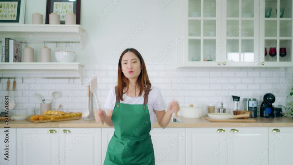 Young Asian woman dancing in the kitchen. The joy of a beautiful woman relaxing in her free time during the weekend in the house Young Asian woman dancing in the kitchen. The joy of a beautiful woman relaxing in her free time during the weekend in the house
