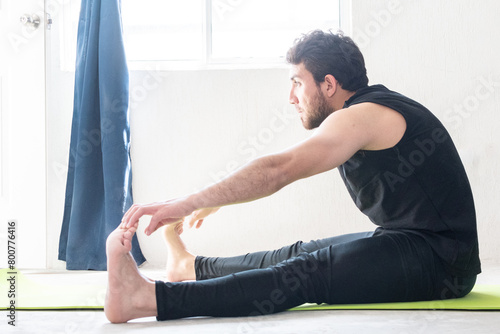 Hombre haciendo estiramientos de pierna en casa  photo