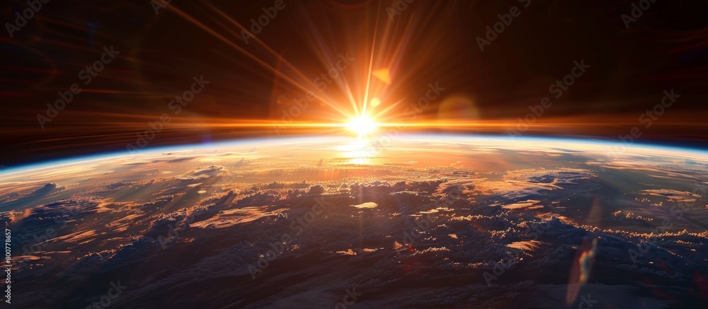 The sun is slowly rising above the view of the Earth from space, creating a stunning moment of light and beauty