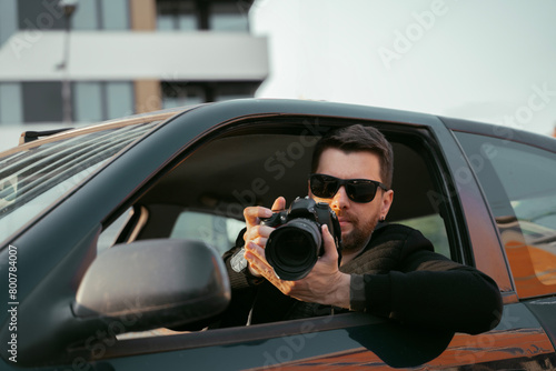 Vászonkép Private investigator sitting in the car and taking pictures, wearing black jacke
