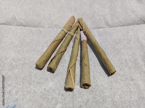 Bidi or Beedi, A beedi is a thin cigarette or mini-cigar filled with tobacco flake and commonly wrapped in a tendu or Piliostigma racemosum leaf tied with a string or adhesive, bidi isolated  photo