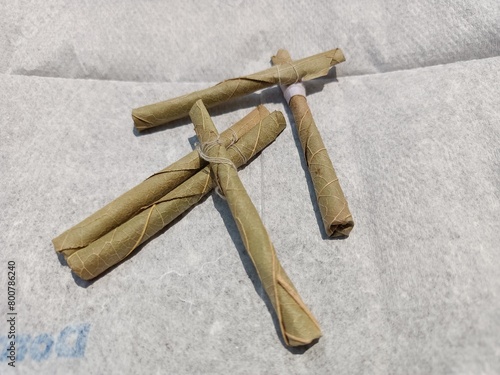 Bidi or Beedi, A beedi is a thin cigarette or mini-cigar filled with tobacco flake and commonly wrapped in a tendu or Piliostigma racemosum leaf tied with a string or adhesive, bidi isolated 