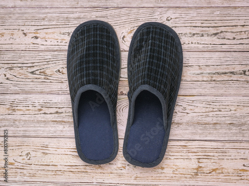 Comfortable men's slippers on a wooden background.