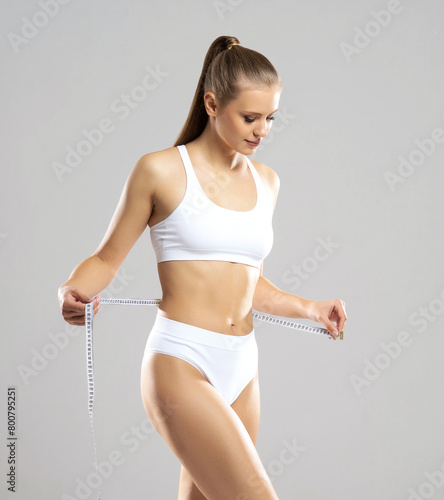 Young, fit and beautiful woman in white swimsuit over white background. The concept of healthcare, diet, sport and fitness.