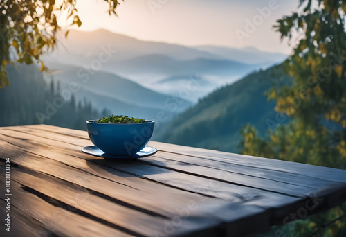 A bowl of fresh greens on a wooden table overlooking a misty mountain landscape at sunrise.