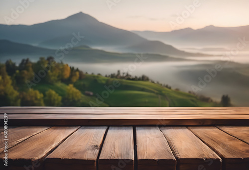 Wooden table overlooking a misty mountain landscape at sunrise, with lush greenery and soft, glowing light.