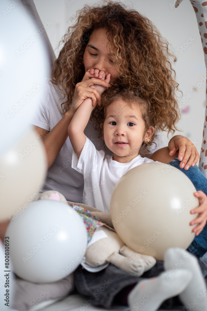 Curly mother and daughter playing in children's room with toys and tent Curly mother and daughter playing in children's room with toys and tent