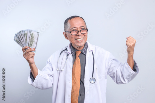 Senior Male Doctor Showing Happiness Getting Reward to Earning Money Dollars Isolated on White Background 
