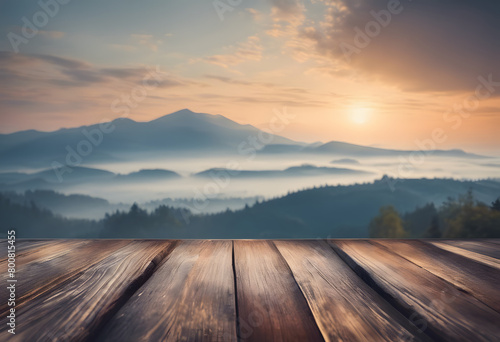 Sunrise over misty mountains with a wooden table in the foreground, creating a serene and picturesque landscape.