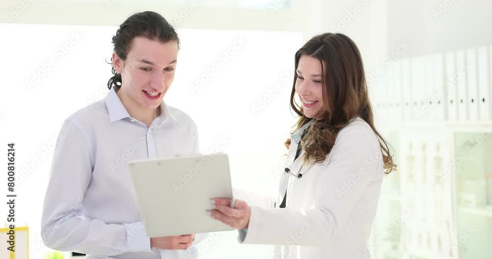 Doctor and patient at a medical consultation laugh and discuss a medical diagnosis Doctor and patient at a medical consultation laugh and discuss a medical diagnosis