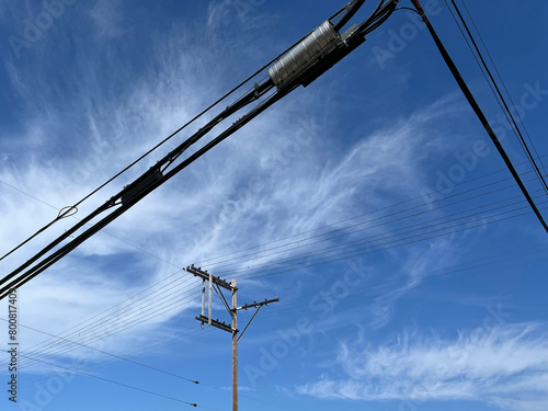 Electricity pylon, power cables and blue sky with vivid cirrus clouds