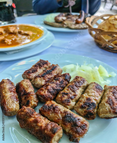 Close up view on grilled cevapcici with salvia in local restaurant on table in the city centre of Podgorica, Montenegro, Balkans, Europe. Balkan local products
