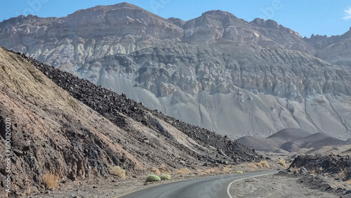 Panoramic view of endless empty road leading to colorful geology of multi hued Artist Palette rock formations in Death Valley National Park near Furnace Creek, California, USA. Black mountains photo