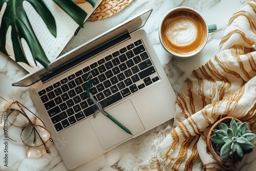 Oerhead shot of modern workspace with sleek laptop, notepad, and cup of coffee, Laptop on marble surface, accompanied by succulent plant, evoke a serene morning. photo