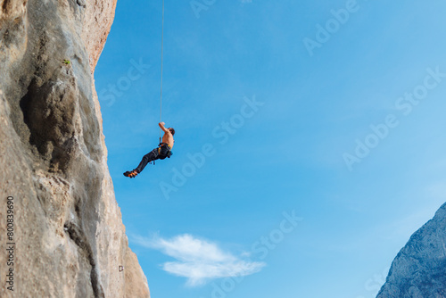 Canvas Print rock climber descends from a route, a climber hangs on a rope against the sky