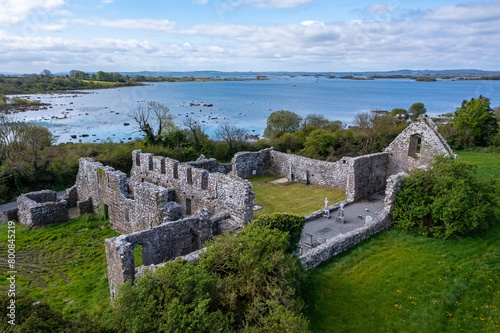Wide-angle view of sunny Annaghdown Abbey with Lough Corrib in background