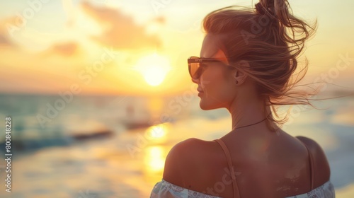 Gracefully adorned in sunglasses  a 40-year-old woman savors the beach s tranquility  her gaze fixed on the sun s radiant embrace