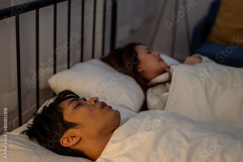 Asian woman feel frustrated from husband snoring while sleep at night.  photo