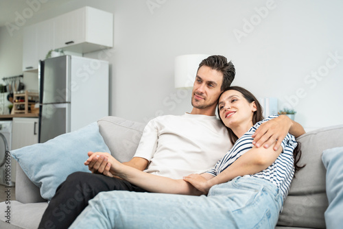 Caucasian young loving couple sitting on sofa in living room at home. 