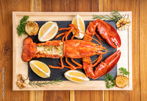 Grilled Lobster with Cheese on black plate, Grilled Canadian Lobster on wooden background.