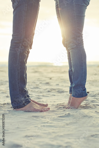 Feet, couple and hug with love on beach for romantic getaway on weekend for anniversary and embrace on vacation. Man, woman and bonding together for intimacy or care, affection and summer holiday. © peopleimages.com