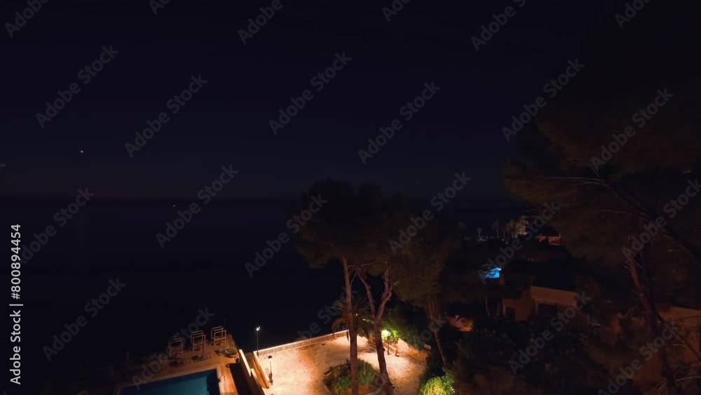Time-lapse drone view captures a stunning sunrise in Palma Mallorca resort, painting the sky with hues of pink, red, and white, overlooking with a pool and swaying trees and fast waves of the sea. Time-lapse drone view captures a stunning sunrise in Palma Mallorca resort, painting the sky with hues of pink, red, and white, overlooking with a pool and swaying trees and fast waves of the sea.