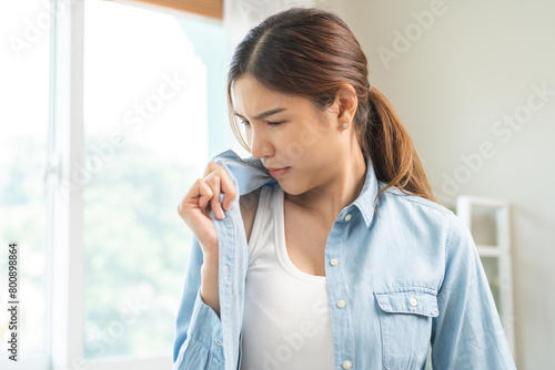 Foto Bad smell nose concept asian young housewife woman having smelling clothes her shirt collar, sniff smelly dirty stinky musty, look disgusting from clothes after washed, laundry out of machine at home