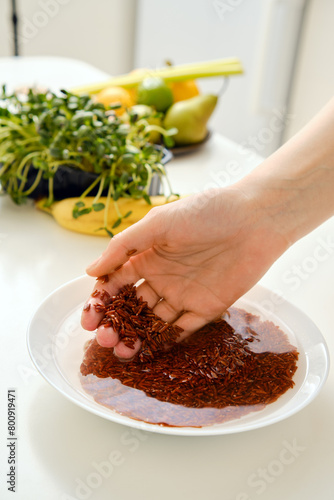 Closeup view of female hand rinsing pink rice in a bowl