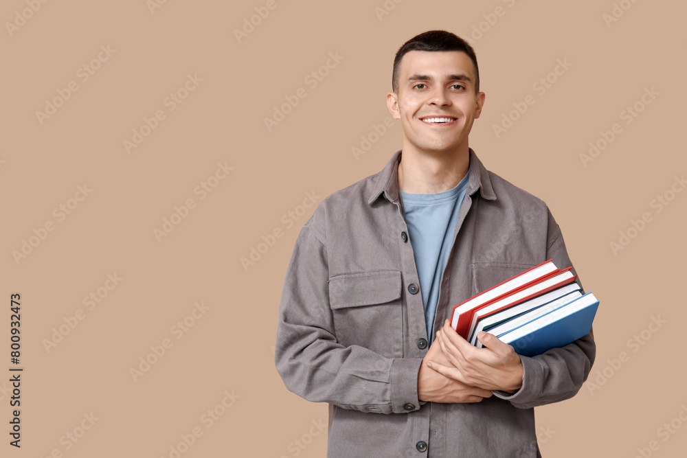 Handsome young man with books on beige background Handsome young man with books on beige background