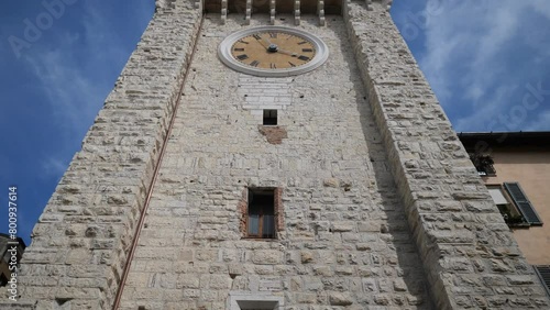  Torre della Pallata brick medieval clock tower building with merlons in typical italian street, Brescia city historical centre. photo