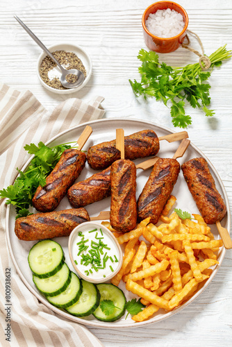 minced beef skewers with potato fries on plate