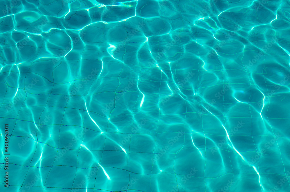 Water in pool with sun reflection. Photography reflection of sun rays on the bottom of the pool..Water surface background, texture.